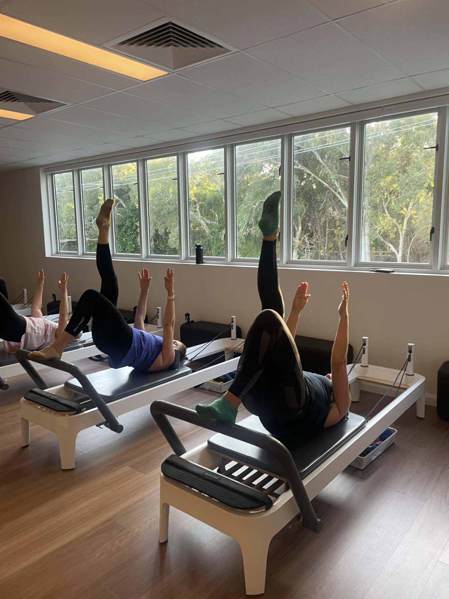 Reformer class in a leg-raise position during a morning session